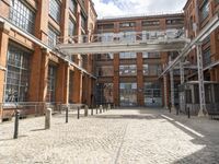 a cobblestone paved courtyard with brick floors and a bridge for traffic to pass