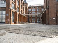 a cobblestone paved courtyard with brick floors and a bridge for traffic to pass