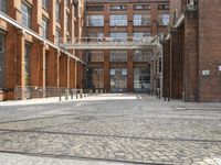 a cobblestone paved courtyard with brick floors and a bridge for traffic to pass