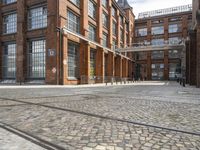 a cobblestone paved courtyard with brick floors and a bridge for traffic to pass