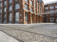 a cobblestone paved courtyard with brick floors and a bridge for traffic to pass