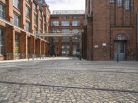 a cobblestone paved courtyard with brick floors and a bridge for traffic to pass