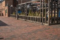 the cobblestone pavement is empty with the clock tower in the background, a woman walks past and shops on the right side