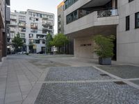 the cobblestone paving in a public plaza with buildings in the background and people walking along