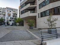 the cobblestone paving in a public plaza with buildings in the background and people walking along