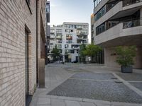 the cobblestone paving in a public plaza with buildings in the background and people walking along