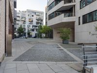 the cobblestone paving in a public plaza with buildings in the background and people walking along