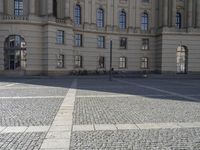 this photo depicts an empty area outside a building with cobblestone floors and windows