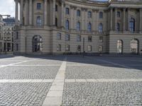 this photo depicts an empty area outside a building with cobblestone floors and windows