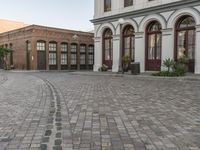 a cobblestone paved plaza and buildings in the middle of downtown with a city skyline