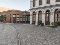 a cobblestone paved plaza and buildings in the middle of downtown with a city skyline