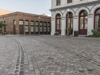 a cobblestone paved plaza and buildings in the middle of downtown with a city skyline