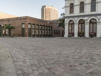 a cobblestone paved plaza and buildings in the middle of downtown with a city skyline