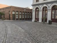 a cobblestone paved plaza and buildings in the middle of downtown with a city skyline