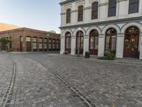 a cobblestone paved plaza and buildings in the middle of downtown with a city skyline