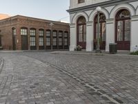 a cobblestone paved plaza and buildings in the middle of downtown with a city skyline