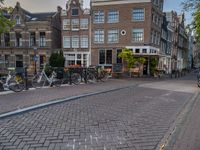 several bicycle racks sit along side a cobblestone road in the middle of a city