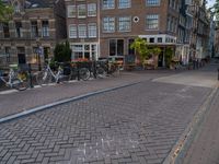 several bicycle racks sit along side a cobblestone road in the middle of a city