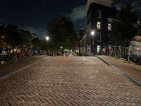 a cobblestone road in front of parked bicycles at night or early mornings, in an urban area