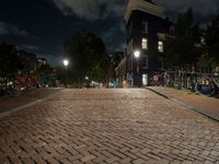 a cobblestone road in front of parked bicycles at night or early mornings, in an urban area