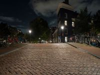 a cobblestone road in front of parked bicycles at night or early mornings, in an urban area