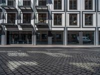 a black and silver building and cars on a cobblestone street in london, england