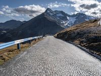 a cobblestone road leads up to some mountains and valleys in the alps mountains