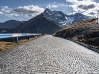 a cobblestone road leads up to some mountains and valleys in the alps mountains