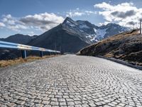 a cobblestone road leads up to some mountains and valleys in the alps mountains