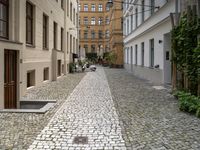 a cobblestone road with a bench in between the buildings and benches on each side