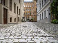 a cobblestone road with a bench in between the buildings and benches on each side