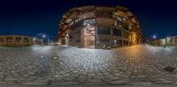 a fish eye view of an empty road at night with buildings lit up in the background