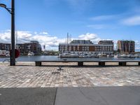 a brick road with stone steps in between parked boats on the side of it, a street lamp and buildings in the background