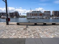 a brick road with stone steps in between parked boats on the side of it, a street lamp and buildings in the background