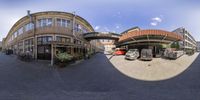 an 360 - view looking at buildings and cars with a red car in front of one and another parked