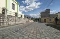 a motorcycle drives down an old brick road between two buildings in the city, with some buildings behind them