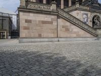 the stairs and stone buildings at the entrance to a large building with a clock on it