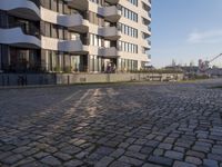a cobble - stone road with a building in the background in the city of gothenburg