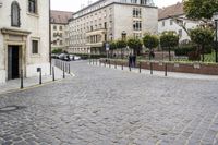 a cobblestone road with buildings and a man holding a sign on it's end