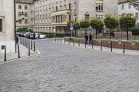 a cobblestone road with buildings and a man holding a sign on it's end