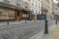 two black post's on a cobble - stone road in paris, france