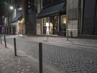 a brick road with poles and a small sign on the side of it, and people walking on it
