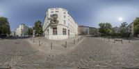 a circle - shaped image of a building on a cobblestone road with trees and buildings behind it