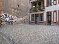 this is an image of two people walking on a cobble stone street by some brick buildings