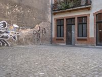 this is an image of two people walking on a cobble stone street by some brick buildings