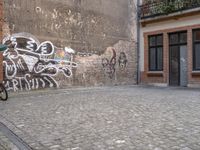 this is an image of two people walking on a cobble stone street by some brick buildings