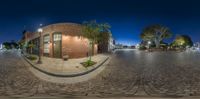 a fisheye lens captures a view of the town from a street corner at night