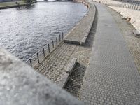 a path that is by the water and has benches lined along it with a bench to either side