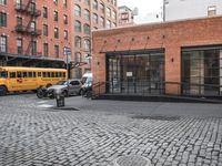 a cobble stone sidewalk with some parked cars and buildings in the background by a street hydrant