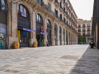 a cobblestone street in an european city on a sunny day with pedestrians on the sidewalk